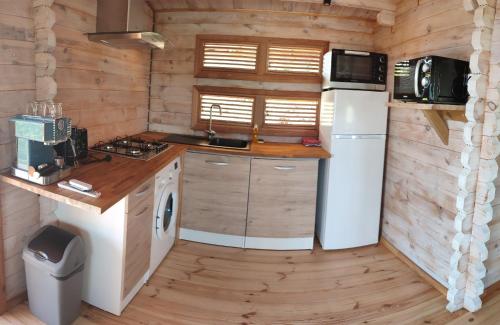 a kitchen in a log cabin with a sink and a refrigerator at Bungalow vert corail in Le Vauclin