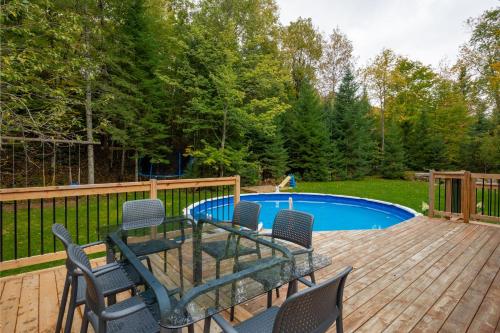 a deck with chairs and a table next to a pool at Chalet La Canopée -familial par excellence MontBlanc in Mont-Blanc