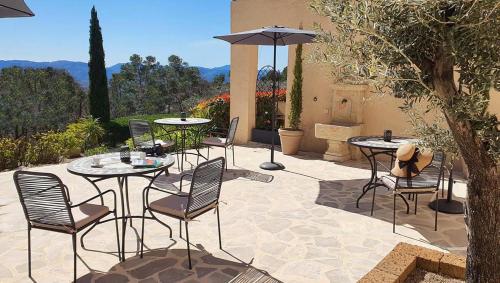 a patio with tables and chairs and an umbrella at Les Hauts de la Riviera in Cabris