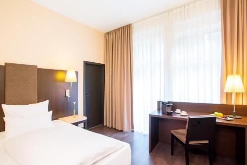 a hotel room with a bed and a desk with a computer at Villa Hotel Frankfurt by MZ HotelCollection in Frankfurt