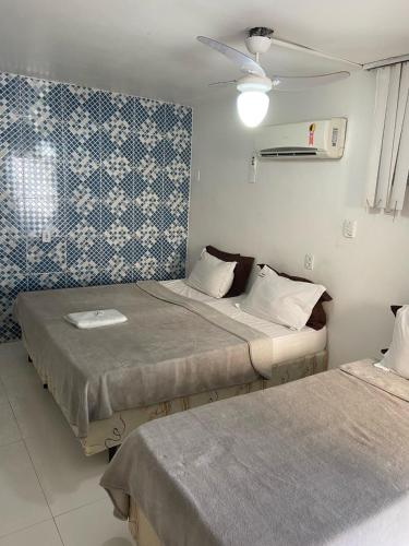 two beds in a room with blue and white wallpaper at Pousada Pinheiro in Campos dos Goytacazes
