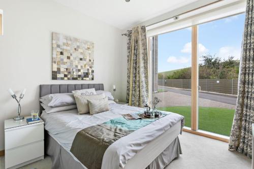 a bedroom with a bed and a large window at Coast at Beachdown in Bigbury