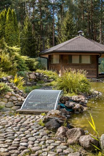 a house with a solar panel next to a pond at Villa Rose & SPA in Mežciems