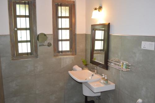 a bathroom with a sink and two mirrors at Villa Tee Four in Digana