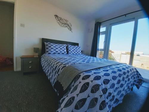 a bedroom with a blue and white bed with a window at The Getaway - Modern 2 Bedroom Brixham Bungalow with sea peeps in Brixham
