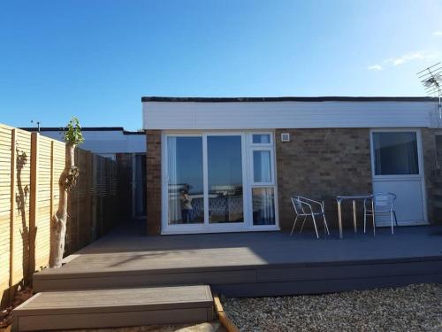 a house with a patio with a table and chairs at The Getaway - Modern 2 Bedroom Brixham Bungalow with sea peeps in Brixham