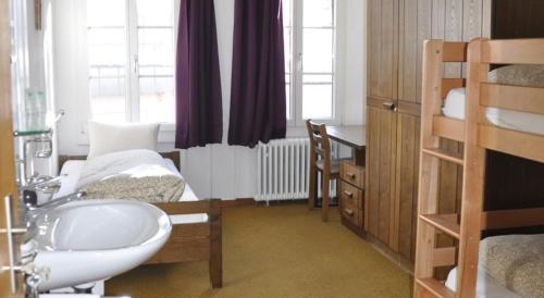 a bedroom with a bed and a sink and a bed gmaxwell gmaxwell gmaxwell at Hostel Engelberg "mein Trail Hostel" in Engelberg