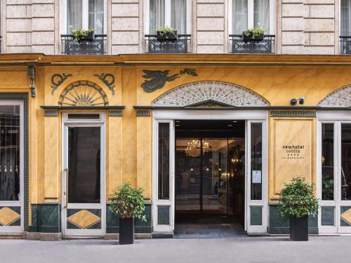 a yellow building with doors and plants in front at New Hotel Roblin in Paris