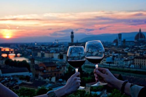 deux personnes tenant des verres de vin devant une ville dans l'établissement Diavoli Rooms, à Florence