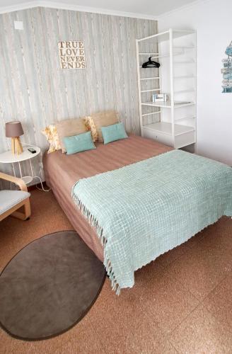 a bedroom with a large bed and a white shelf at Casa Faroleiro in Nazaré