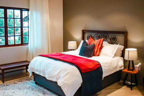 a bedroom with a large bed with orange and white pillows at The Aloes Farm - The Studio & The Gallery in Hilton