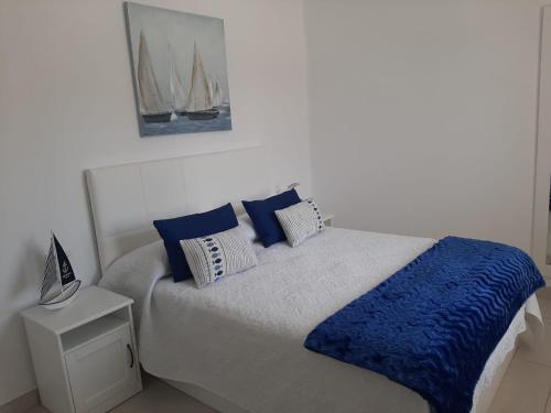1 dormitorio con 1 cama con almohadas azules y blancas en Marina Senator, en Costa Teguise