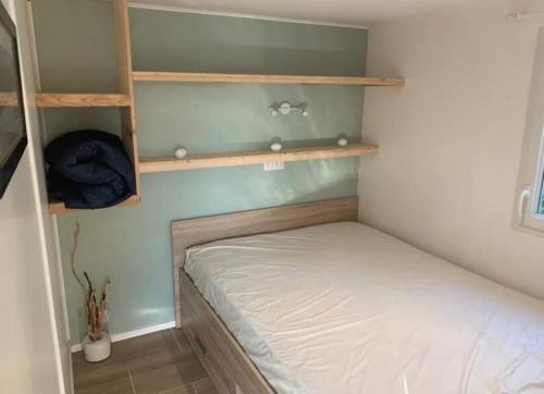 een kleine slaapkamer met een bed en planken bij Logement - Les Epesses in Les Épesses