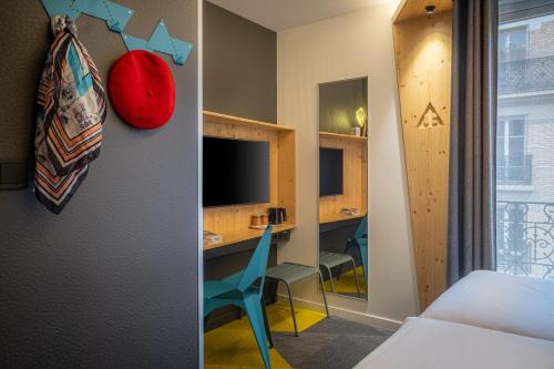 a room with a bed and a desk with a monitor at Urban Bivouac Hotel in Paris