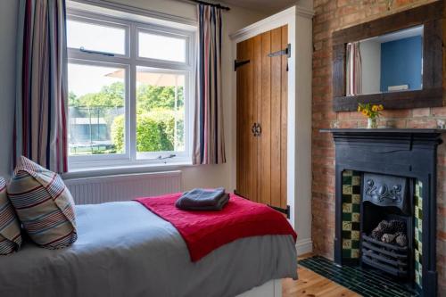 een slaapkamer met een bed en een open haard bij Heather Cottage in Brockenhurst