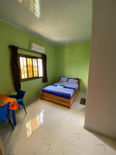 a bedroom with a bed and a table and a window at Appartements Lome Marie Antoinette in Atigan