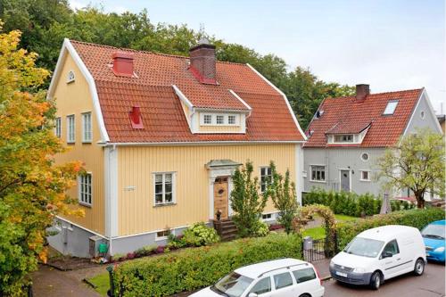 een geel huis met twee auto's geparkeerd op een parkeerplaats bij 5:ans Bed & Breakfast in Göteborg