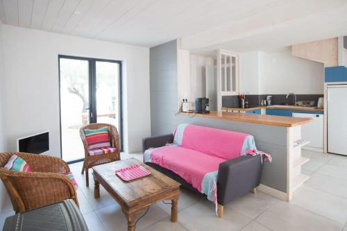 ein Wohnzimmer mit einem rosa Sofa und einer Küche in der Unterkunft Les Maisons de l'Olivette in La Couarde-sur-Mer