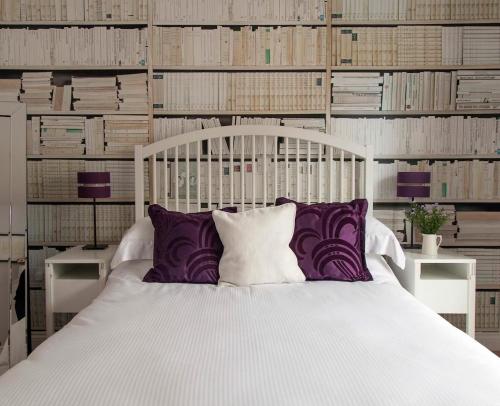 a white bed with purple pillows in a room with books at Number Two in Southampton