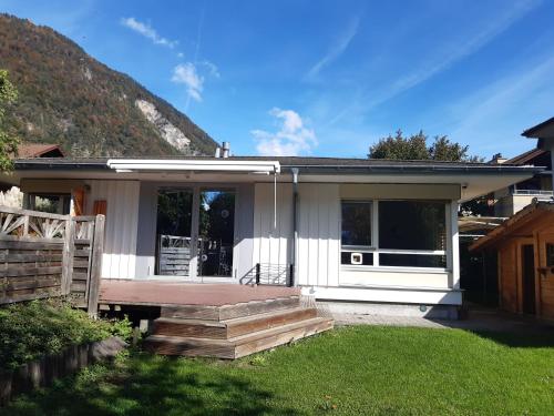 a small white house with a porch and a yard at Adventure Guesthouse Interlaken in Interlaken