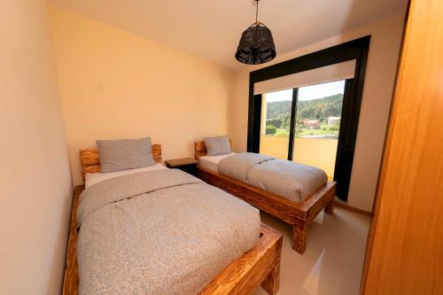 um quarto com 2 camas e uma janela em Apartamento Pinto Playa de Langosteira en Finisterre con vistas al mar em San Martín de Arriba