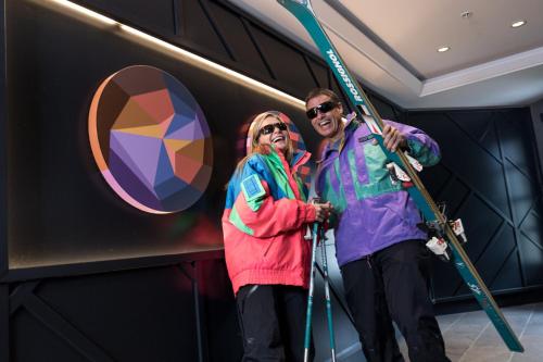 a man and woman holding skis in a room at The Crystal Lodge in Whistler