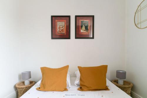a bedroom with a bed with two pillows and two pictures at Résidence Epinat - Appartements centre & parking in Vichy