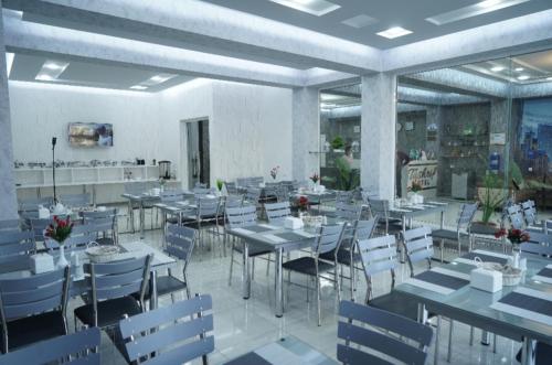 jadalnia ze stołami i białymi krzesłami w obiekcie TASHRIF HOTEL w Karszy