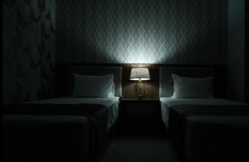 a dark room with two beds and a lamp at TASHRIF HOTEL in Qarshi