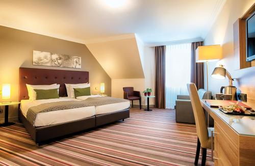 a hotel room with a bed and a desk at Leonardo Hotel Hamburg Stillhorn in Hamburg