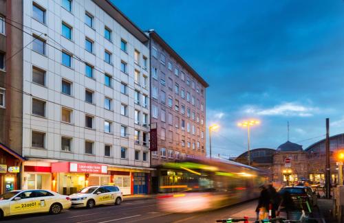 a bus driving down a city street with buildings at Leonardo Hotel Frankfurt City Center in Frankfurt/Main