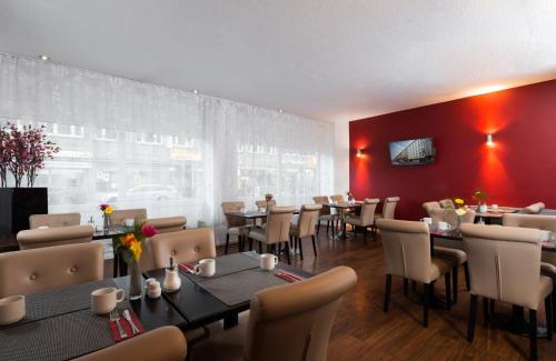 ein Restaurant mit Tischen und Stühlen und einer roten Wand in der Unterkunft Leonardo Hotel Frankfurt City Center in Frankfurt am Main