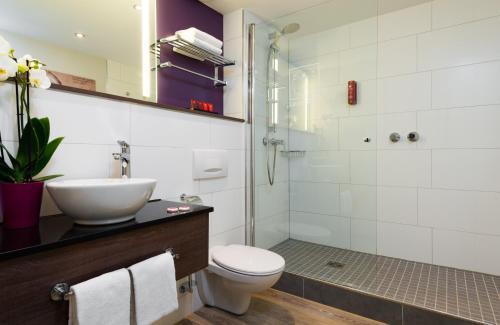 uma casa de banho com um lavatório, um WC e um chuveiro em Leonardo Hotel Frankfurt City Center em Frankfurt