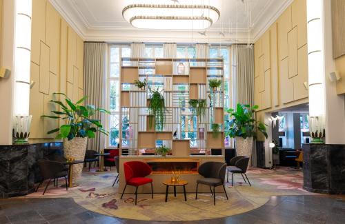a lobby with chairs and a table and plants at Leonardo Royal Hotel Berlin Alexanderplatz in Berlin