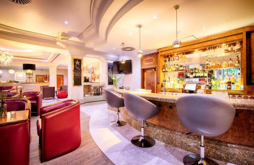 eine Bar mit Stühlen und einer Theke in einem Restaurant in der Unterkunft Leonardo Hotel Düsseldorf City Center in Düsseldorf