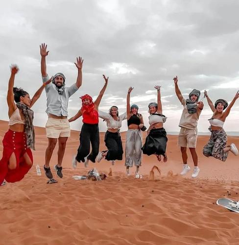 a group of people jumping in the air on the beach at Sahara Luxury Tented Camp in Merzouga