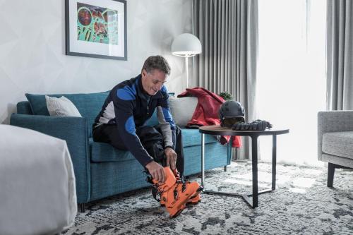 a man sitting on a couch playing with a leg prosthesis at The Crystal Lodge in Whistler