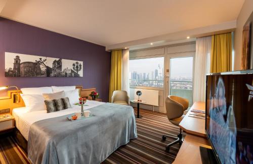 a hotel room with a bed and a flat screen tv at Leonardo Royal Hotel Frankfurt in Frankfurt/Main