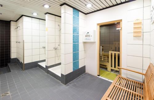a bathroom with white tiled walls and a wooden bench at Leonardo Royal Hotel Düsseldorf Königsallee in Düsseldorf