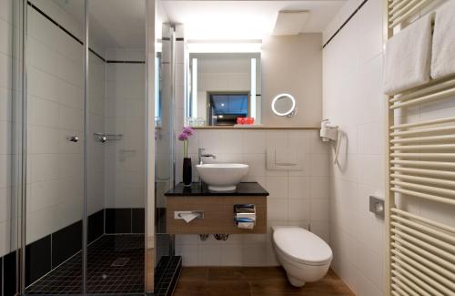 ein Bad mit einem WC, einem Waschbecken und einer Dusche in der Unterkunft Leonardo Hotel Munich City Olympiapark in München