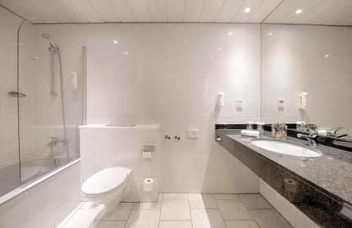 uma casa de banho com um WC, um lavatório e um chuveiro em Leonardo Hotel Düsseldorf Airport Ratingen em Ratingen