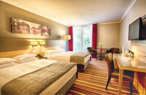 Pokój hotelowy z 2 łóżkami i biurkiem w obiekcie Leonardo Hotel Düsseldorf Airport Ratingen w mieście Ratingen