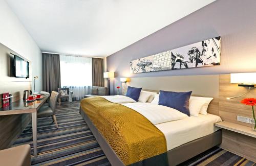 ミュンヘンにあるレオナルド ホテル ミュンヘン シティ ノースのベッドとデスクが備わるホテルルームです。
