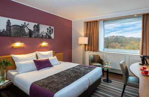 une chambre d'hôtel avec un lit et une fenêtre dans l'établissement Leonardo Hotel Frankfurt City South, à Francfort-sur-le-Main