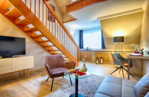 a living room with a staircase with a couch and a table at Leonardo Hotel Heidelberg Walldorf in Walldorf