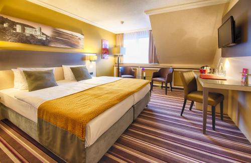 a hotel room with a bed and a table and chairs at Leonardo Hotel Heidelberg Walldorf in Walldorf