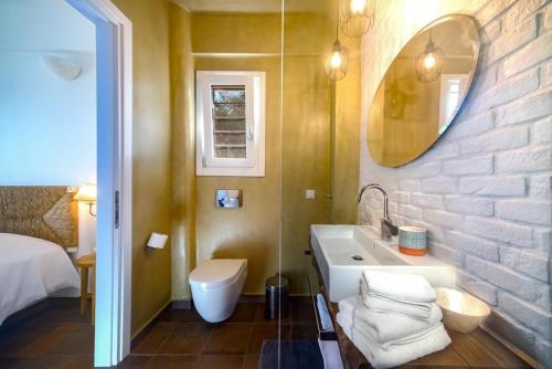 a bathroom with a sink and a toilet and a mirror at Apeiron I Villa by PaxosRetreats in Oziás