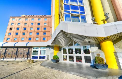 a building with yellow columns and a building at Leonardo Hotel Köln in Cologne