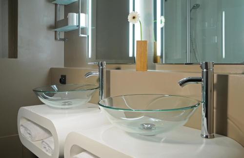 un baño con 2 tazones de cristal en un lavabo en Leonardo Boutique Hotel Munich en Múnich