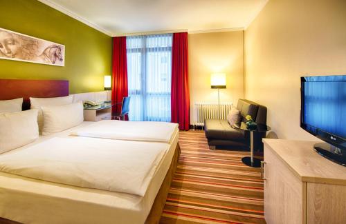 a hotel room with two beds and a television at Leonardo Hotel & Residenz Muenchen in Munich